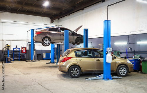 Obraz na plátně Car on lift in mechanic shop or garage, interior of auto repair workshop, vehicles inside maintenance