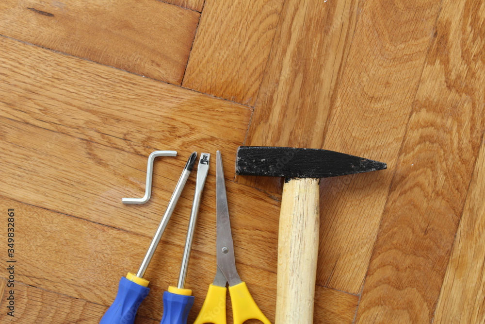 Hammer and tools on wooden parquet.
