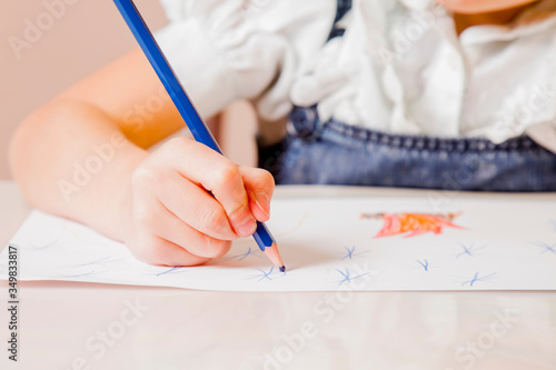 Investment in the future: learning and education of great artist. Close up young beautiful girl draws with colored pencils.