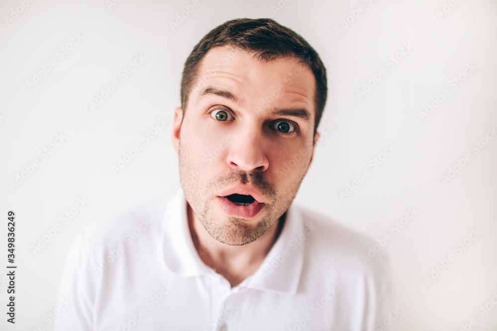 Young man isolated over white background. Portrait of wondered and amazed guy looking straight close on camera. Emotional man. Young man isolated over white background. Portrait of wondered and amazed guy looking straight close on camera. Emotional man.