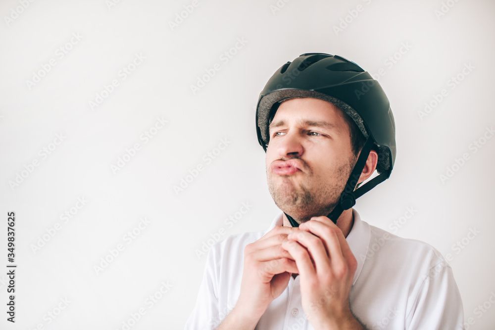 Young man isolated over white background. Serious confident guy closing helmet on his head. Get ready for exercising. Young man isolated over white background. Serious confident guy closing helmet on his head. Get ready for exercising.