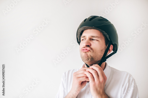 Young man isolated over white background. Serious confident guy closing helmet on his head. Get ready for exercising. © Vlad