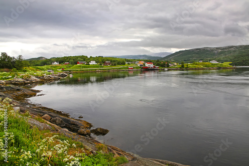 Beautiful landscape along with waters edge with a village, church & mountains in the background, Saltstraumen, Municipality of Bodo, Nordland county, Norway.