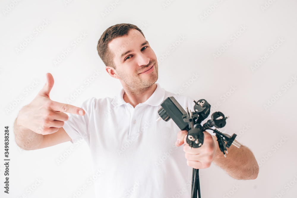 Young man isolated over white background. Guy hold black inputs cords and electrical cables in hans and point on them. Posing on camera. Young man isolated over white background. Guy hold black inputs cords and electrical cables in hans and point on them. Posing on camera.