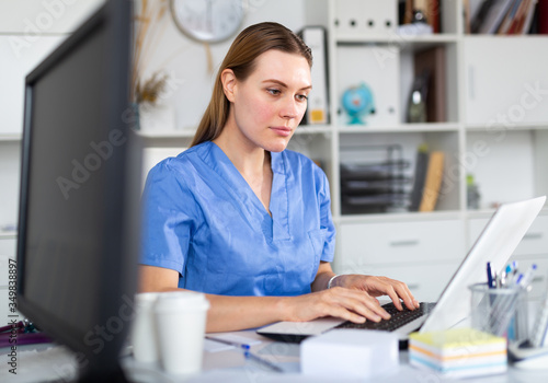 Female doctor working on laptop in clinic office
