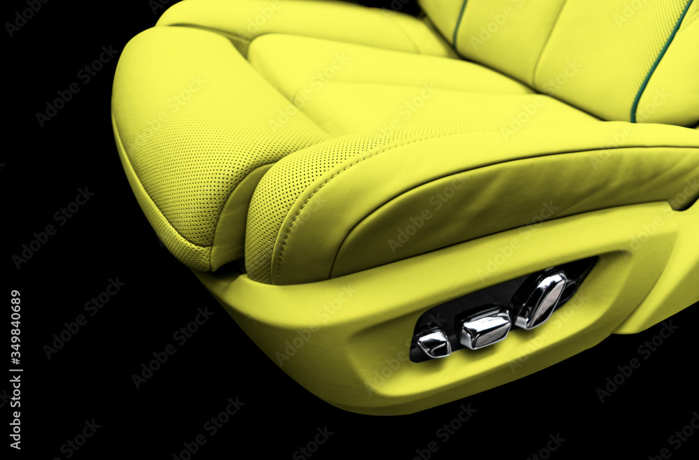 Yellow leather interior of the luxury modern car. Perforated yellow leather comfortable seats with stitching isolated on black background. Modern car interior details. Car detailing. Car inside