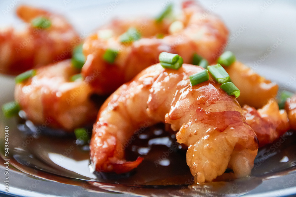 Large pacific prawns in spicy chili sauce with chopped green onions on a glass plate. Large pacific prawns in spicy chili sauce with chopped green onions on a glass plate.