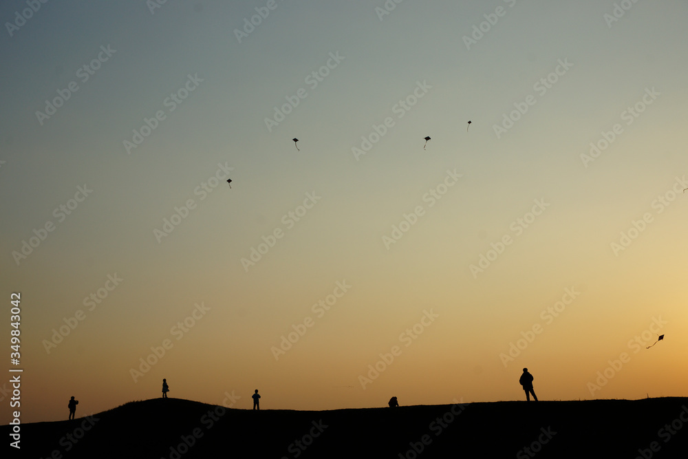 silhouette of a group of person flying kites on sunset
