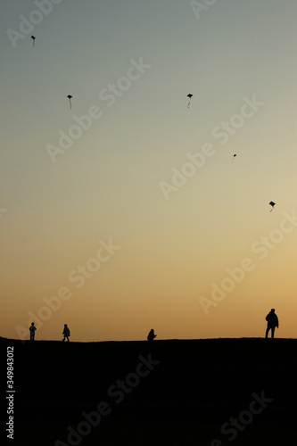 silhouette of a group of person flying kites on sunset 