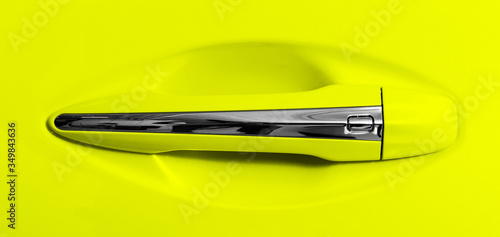 The modern door handle of a yellow car. Car detailing. Car exterior details. Closeup Car door handle. Car equipment concept.