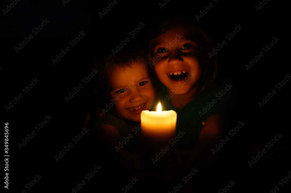 happy laughing kids siblings boy and girl admires a burning wax candle in the evening at home happy laughing kids siblings boy and girl admires a burning wax candle in the evening at home