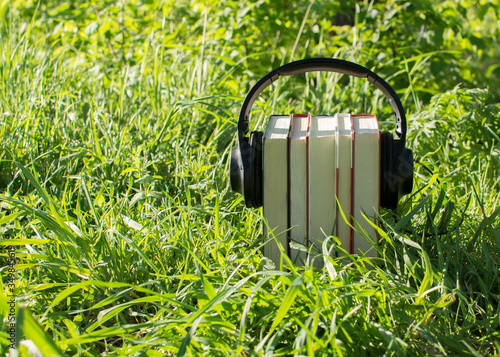 audiobook concept with headphones and books, in nature