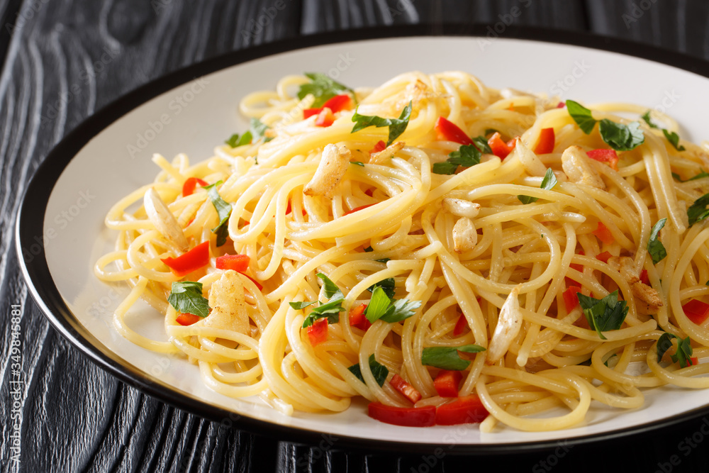 Tasty aglio e olio pasta with fried garlic, parsley and hot pepper close-up in a plate. horizontal Tasty aglio e olio pasta with fried garlic, parsley and hot pepper close-up in a plate. horizontal