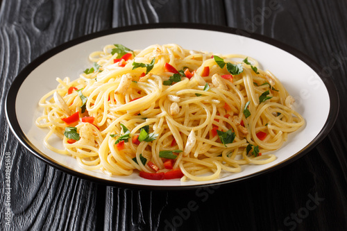 Recipe for classic aglio e olio pasta with fried garlic, parsley and hot pepper close-up in a plate. horizontal