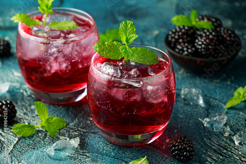 Refreshing Blackberry cocktail with ice and mint on rustic background