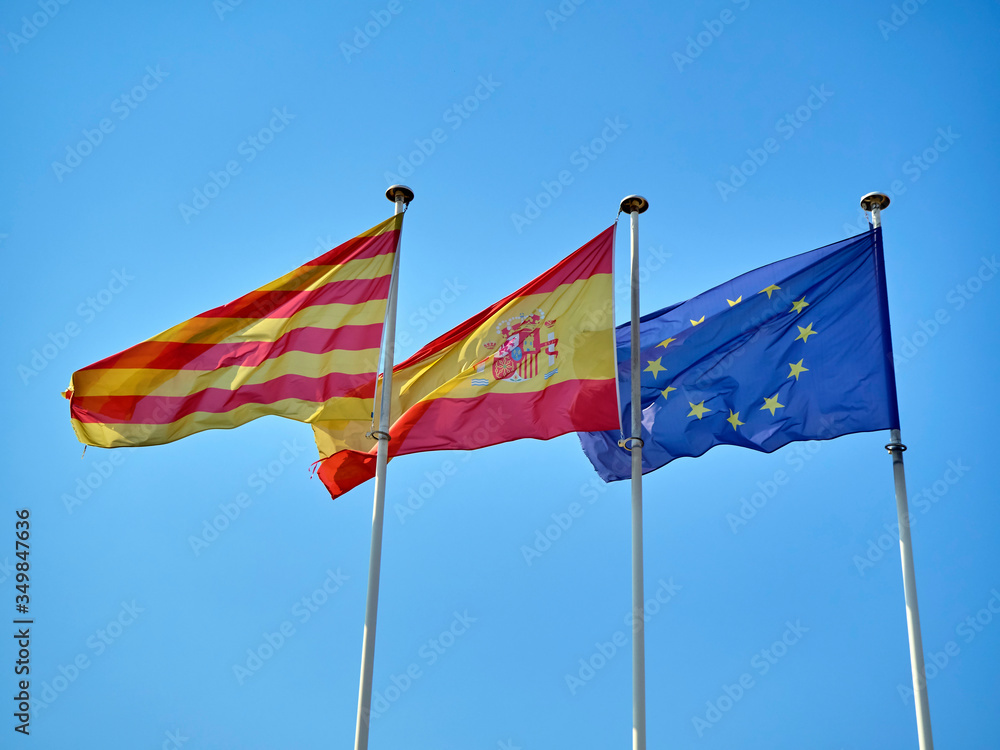 Official flags of Catalonia, Spain and The European Union (EU) waving on a blue sky. Official flags of Catalonia, Spain and The European Union (EU) waving on a blue sky.