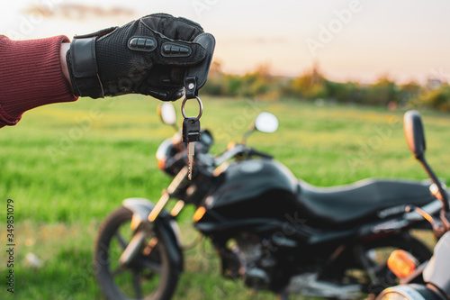 man holding a dark transport key on a background of motorcycles