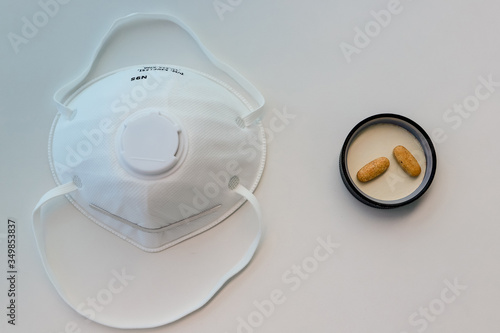 Protective mask N95 respirator and pills on white table top view. COVID-19 concept.
