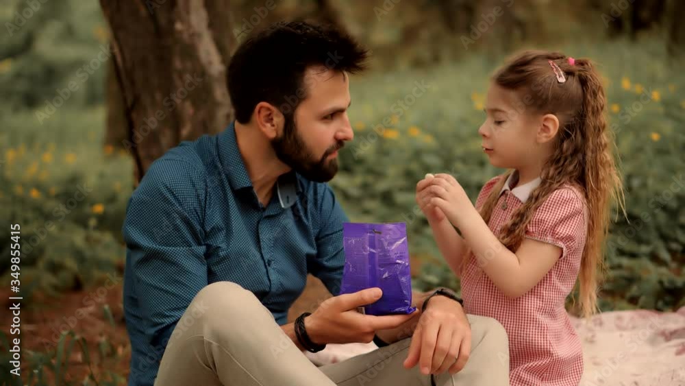 Daughter With Cheerful Father Eat Candy.Happy Beautiful Family Relaxing Together In Park.Adorable Daughter Kid With Father Eating Sweets.Little Cute Preschool Girl Having Fun And Eats Jelly Candies. Daughter With Cheerful Father Eat Candy.Happy Beautiful Family Relaxing Together In Park.Adorable Daughter Kid With Father Eating Sweets.Little Cute Preschool Girl Having Fun And Eats Jelly Candies.