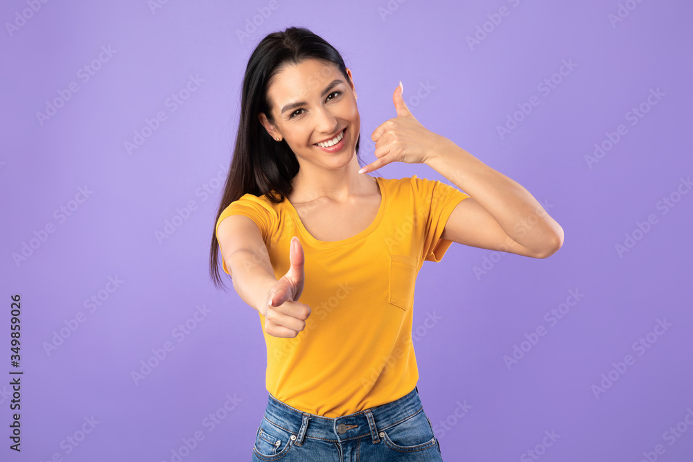 Woman pointing index finger on camera, doing phone gesture Woman pointing index finger on camera, doing phone gesture