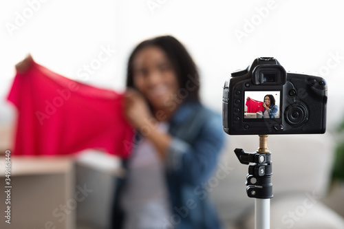 Camera Recording Young Black Woman Unboxing Parcel With New Clothes At Home