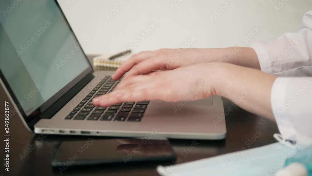 Woman sitting at desk and connecting with her laptop, she is working and typing on the keyboard, hands close up Woman sitting at desk and connecting with her laptop, she is working and typing on the keyboard, hands close up