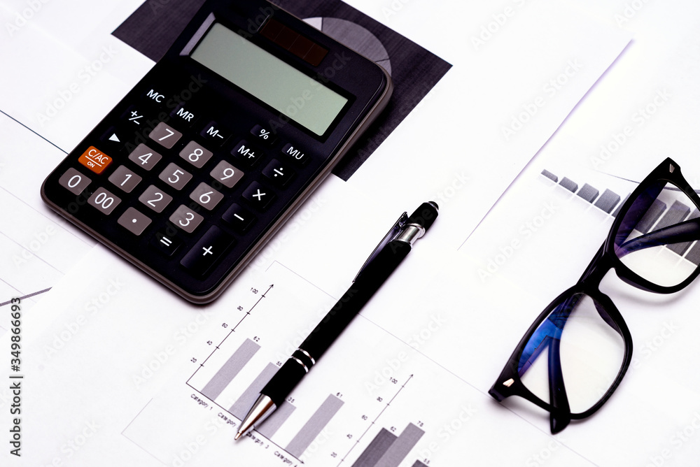 Top view Close up of business working data document graph chart report marketing research calculator pen glasses documents on the table, office workplace.Business office concept. Top view Close up of business working data document graph chart report marketing research calculator pen glasses documents on the table, office workplace.Business office concept.