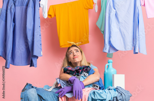 Housewife is looking up, leaning on heap of dirty clothes