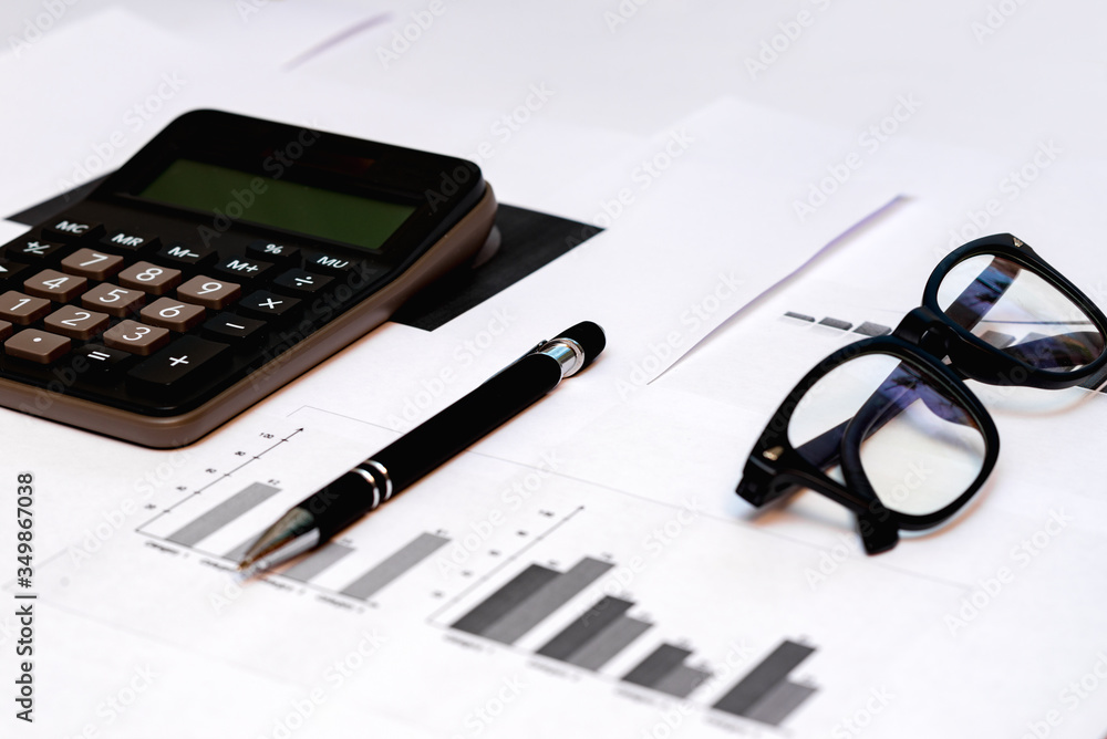 Top view Close up of business working data document graph chart report marketing research calculator pen glasses documents on the table, office workplace.Business office concept. Top view Close up of business working data document graph chart report marketing research calculator pen glasses documents on the table, office workplace.Business office concept.