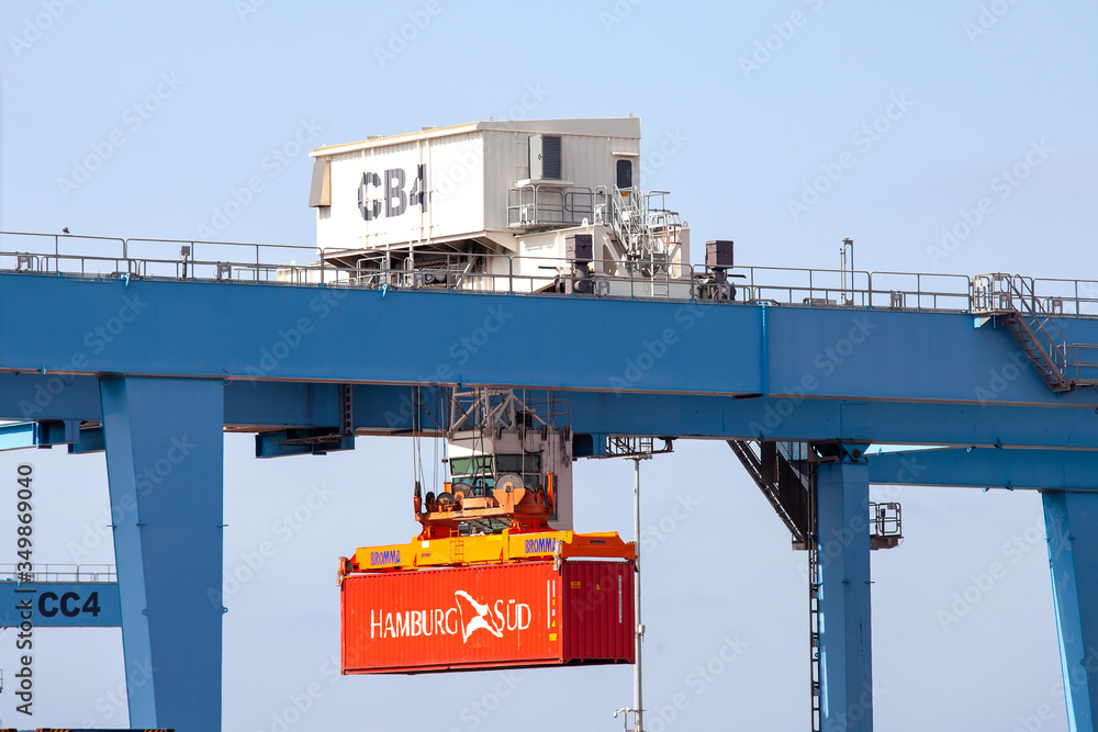 modern container handler carrying a large red steel... Container handler lifting a Red Hamburg Sud Shipping container at ...