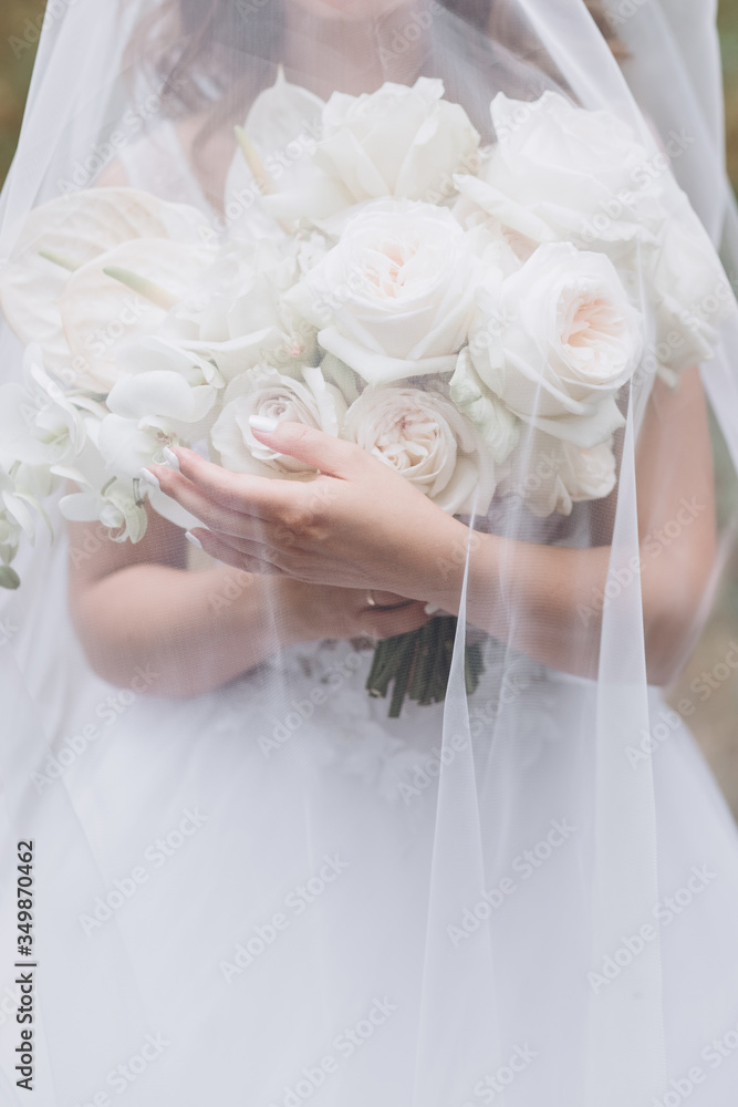 Naklejka premium bride in a white dress with a chic bouquet in her hands. Luxury wedding bouquet. The girl is holding flowers - roses, peonies, archedes.