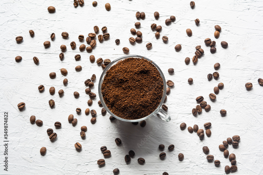 A Cup filled with coffee beans. Coffee beans are scattered on the white surface of the table A Cup filled with coffee beans. Coffee beans are scattered on the white surface of the table