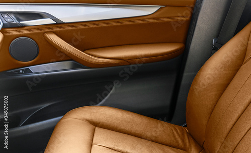 Brown leather interior of the luxury modern car. Perforated brown leather comfortable seats with stitching isolated on black background. Modern car interior details. Car detailing. Car inside © Aleksei