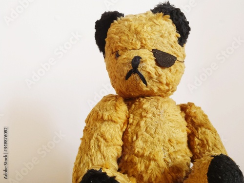 Fotografia Close-up Of Teddy Bear Wearing Costume Eye Patch Against Wall