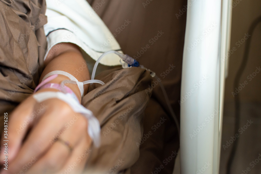 Fototapeta premium The young woman, lying on the bed with an arm, sent a solution of saline solution to the hospital for treatment at the hospital.