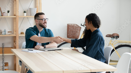 Bilde på lerret Happy businessman shaking hands with diverse woman job seeker
