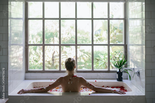 Young adult woman relaxing in bath with tropical flowers