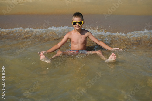 Children on the ocean. A young boy in sunglasses swimming in the sea. Kid on vacation. Family travel. Learning to swim.