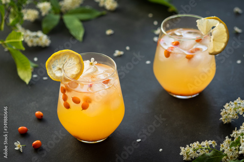 Photography Fresh cocktail with sea buckthorn, juice, and ice in glass on dark background