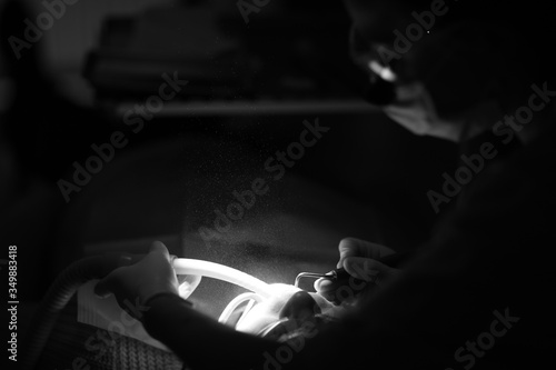 Hands of a dentist with a tool during medical procedures in the light of a spotlight