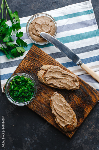 Fresh homemade chicken liver pate with herbs. Bread bruschetta with liver pate with onion, cucumber and radish. Top view, side view on a dark background. space for text.