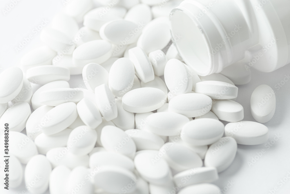 white Pills, tablets, medical drugs or food supplement spilling out of bottle