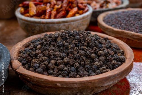 Indian spices collection, dried black peppercorns and another spices in clay bowls