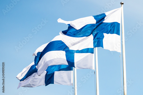 Three finnish national flags on the wind against the blue sky photo