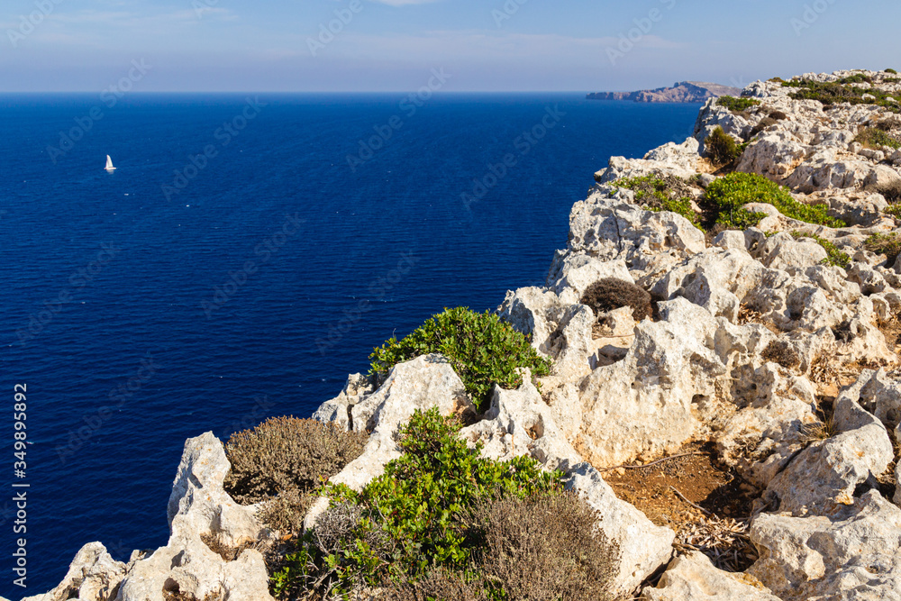 views of the northern cliffs of the island of menorca. Seascape with boat in the background. (balearic islands, spain) views of the northern cliffs of the island of menorca. Seascape with boat in the background. (balearic islands, spain)