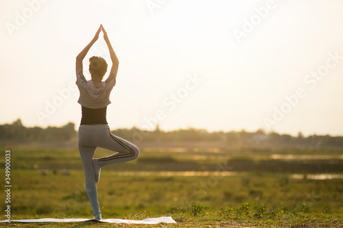 Fototapeta Naklejka Na Ścianę i Meble -  Portrait of a Young Woman performing Yoga outside in sunny bright light.