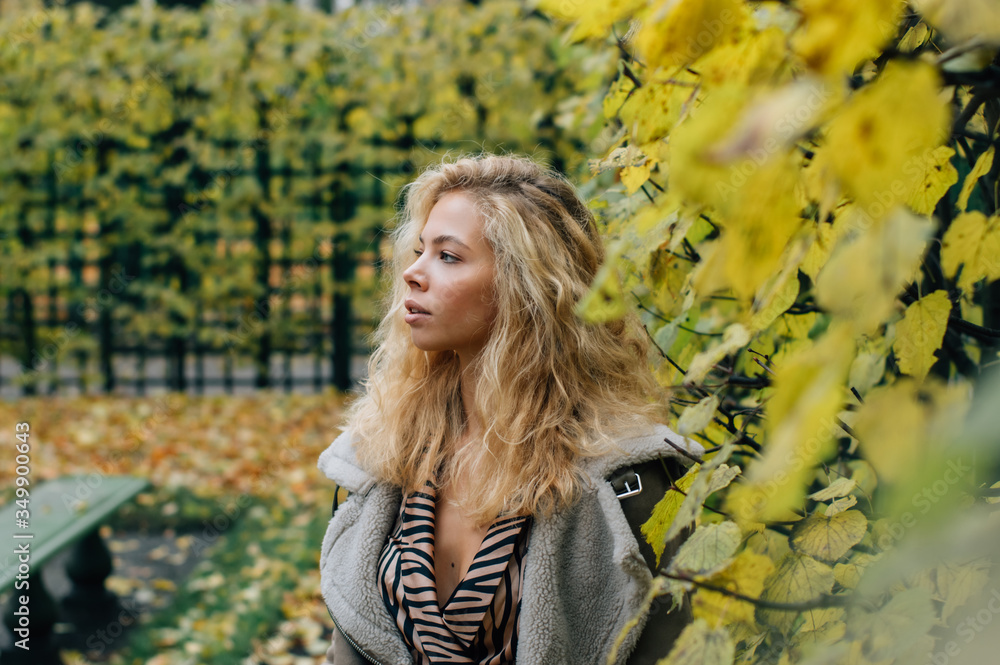 Young blond girl staying near trees in public park Young blond girl staying near trees in public park