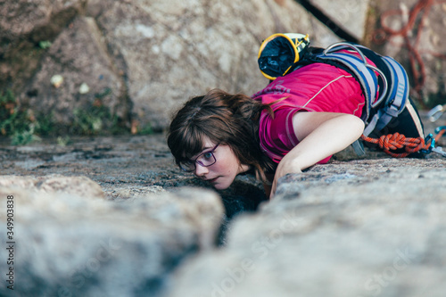 Young strong girl rock climber in a bright T-shirt climbing on a rock.