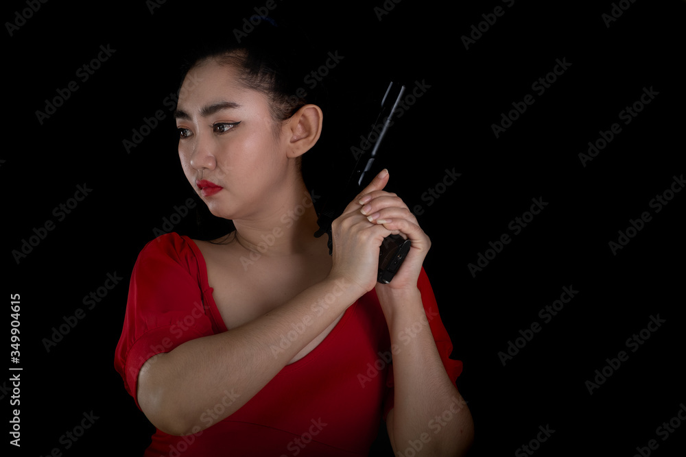 Fototapeta premium Portrait beautiful Asia woman wearing a rad dress one hand holding pistol gun 11mm. at the black background, Young sexy girl long hair with a handgun, Pretty women stand with a guns