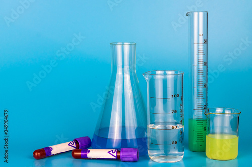 Medical laboratory glassware with chemical reagents and test tubes with blood analysis on a blue background. Copy space.
